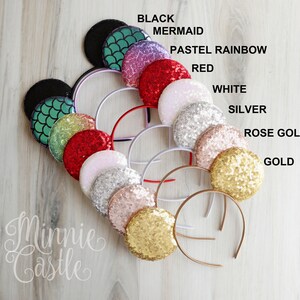 May include: A variety of Minnie Mouse ears with different colored sequins. The colors include black, mermaid, pastel rainbow, red, white, silver, rose gold, and gold. The ears are arranged in a circle on a wooden surface. The text "Minnie Castle" is written in cursive at the bottom of the image.