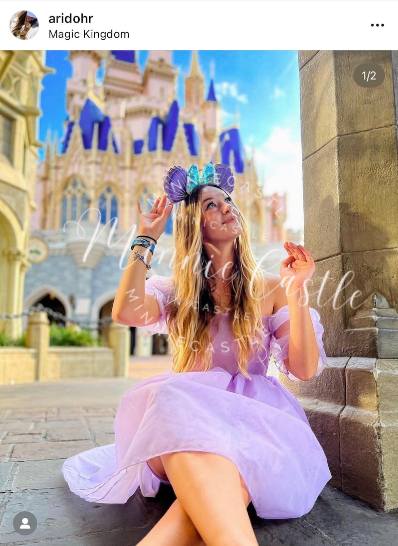 May include: A person wearing a lavender off-the-shoulder dress and a headband with purple and blue ears, posing in front of a castle. The image has the text "Minnie Castle" in a cursive font.