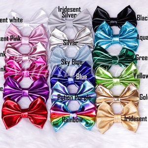 Puede incluir: Una colecci&oacute;n de 14 lazos para el pelo de color s&oacute;lido e iridiscente. Los lazos est&aacute;n dispuestos en dos filas, la fila superior presenta lazos de color blanco iridiscente, plata iridiscente, negro, rosa iridiscente, aqua y plata. La fila inferior presenta lazos de color rosa, azul cielo, verde, rosa intenso, azul, verde amarillo, morado, morado poci&oacute;n, dorado, rojo, arco&iacute;ris y dorado iridiscente.