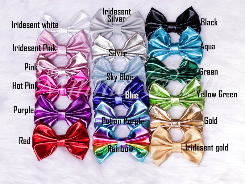 Puede incluir: Una colecci&oacute;n de 14 lazos para el pelo de color s&oacute;lido e iridiscente. Los lazos est&aacute;n dispuestos en dos filas, la fila superior presenta lazos de color blanco iridiscente, plata iridiscente, negro, rosa iridiscente, aqua y plata. La fila inferior presenta lazos de color rosa, azul cielo, verde, rosa intenso, azul, verde amarillo, morado, morado poci&oacute;n, dorado, rojo, arco&iacute;ris y dorado iridiscente.