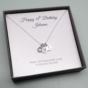 May include: A sterling silver necklace with three charms, presented in a gift box. The charms include a blue crystal, the number "18", and a disc with the letter "J". The box reads "Happy 18th Birthday Julianne".