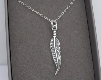 May include: A silver necklace with a feather pendant. The feather is detailed and has a textured surface.
