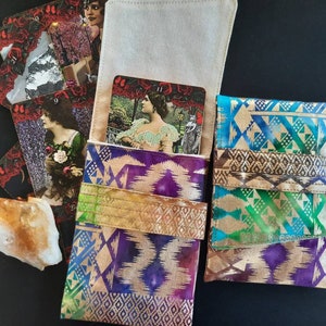 Puede incluir: Tres bolsas de tela con coloridos patrones geométricos. Las bolsas están hechas de una tela suave y texturizada con un brillo metálico dorado. Las bolsas están diseñadas para guardar cartas de tarot u otros artículos pequeños.