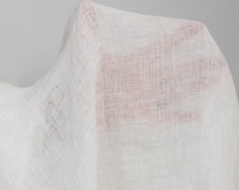May include: White sheer linen fabric with a textured weave. The fabric is draped and folded, creating soft folds and wrinkles.