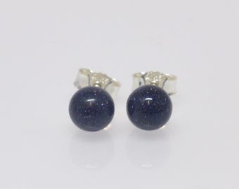 May include: A pair of silver stud earrings with round blue gemstone accents. The gemstones have a speckled texture.