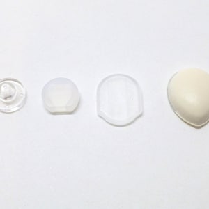 Op de afbeelding: Vier verschillende maten doorzichtige plastic oordopjes en een witte oordop.