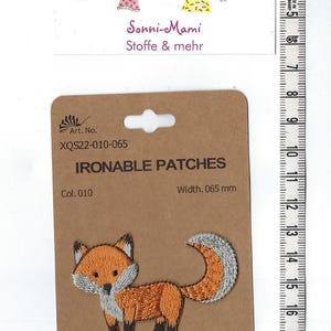 Könnte beinhalten: Bügeleisen-Aufnäher mit einem Cartoon-Fuchs mit orangefarbenem Körper, weißer Brust und grauem Schwanz. Der Aufnäher ist mit "Ironable Patches" und "Col. 010" beschriftet und hat eine Breite von 0,65 mm.