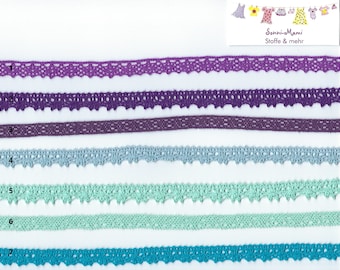 May include: A collection of decorative lace trims in various colours, including purple, blue, and green. The trims feature different patterns and scalloped edges. A ruler with measurements in centimetres is visible. The text "Sonni-Mami Stoffe & mehr" is in the upper right corner.