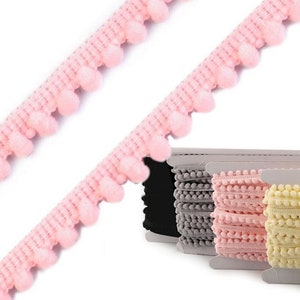 Könnte beinhalten: Spulen mit rosa, gelbem, weißem und grauem Pompon-Zierband. Das Band besteht aus weichen, flauschigen Pompons.