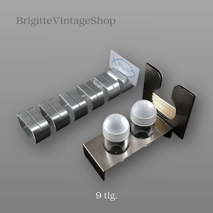 Könnte beinhalten: Ein Edelstahl-Tischset mit Salz- und Pfefferstreuer, Zahnstocherhalter und Serviettenringen. Das Set enthält eine kleine Karte mit dem Wort "Brigitte". Der Text "BrigitteVintageShop" steht oben.