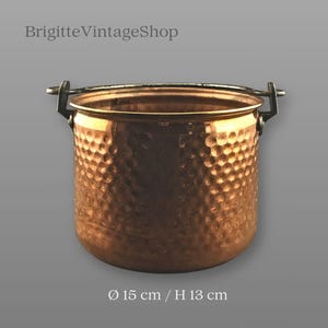 Pode incluir: Um pote de metal martelado cor de cobre com uma alça. O pote é cilíndrico com uma textura martelada e uma alça de metal escuro. O texto "BrigitteVintageShop" está no topo. O pote tem 15 cm de diâmetro e 13 cm de altura.
