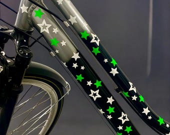 May include: A silver bicycle frame with black and white star stickers. The stars are green in the center.