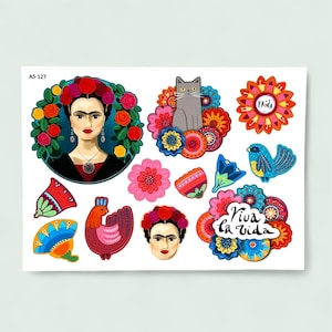 Könnte beinhalten: Ein Bogen mit bunten Aufklebern mit Frida Kahlo-Porträts, Blumen, einer Katze und einem Vogel. Die Aufkleber enthalten die Texte "Frida" und "Viva la Vida". Die Aufkleber sind in verschiedenen Farben, darunter Rot, Blau und Orange.