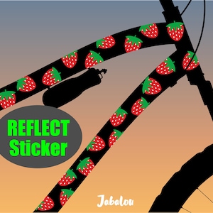 May include: Black silhouette of a bicycle with a reflective sticker on the frame. The sticker features a repeating pattern of red strawberries with green leaves on a black background. The text "REFLECT STICKER" is printed in green on a gray oval. The text "Jabalou" is printed in white at the bottom of the image.