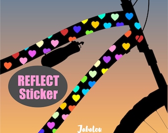 May include: A black bicycle frame with a colorful heart-shaped reflective sticker. The sticker is on the top tube of the frame and reads "Reflect Sticker".