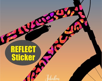 May include: A black bicycle frame with a pink, orange, and yellow reflective sticker. The sticker has a  "Reflect Sticker" text on it. The bicycle frame is silhouetted against a sunset background.