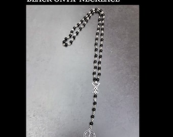 Könnte beinhalten: Schwarze Onyx-Rosenkranz-Halskette mit silbernem Pentagramm- und Sigil-Anhänger. Handgefertigt von Gypsygold.