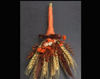 Puede incluir: Un pequeño besom naranja y marrón con tallos de trigo secos y flores naranja y blancas. El besom está atado con una cinta marrón y el texto "Samhain Altar Besom" está en la parte superior de la imagen. El texto "Handcrafted By Gypsygold" está en la parte inferior de la imagen.