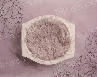 May include: A white wooden bowl with a soft, light pink faux fur insert. The bowl is on a light purple background with a floral pattern.