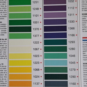 May include: A color chart for rayon thread with a variety of green, blue, purple, and pink shades. The chart is labeled "Rayon" and "Madeira".