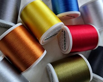Può includere: Assortimento di bobine di filo da ricamo in vari colori, tra cui oro, argento, rosso, blu, verde e arancio. Le bobine sono etichettate "Madeira" e "100% Poliestere".