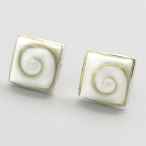 May include: A pair of square stud earrings featuring a white shell inlay with a natural tan spiral pattern. Each square shell piece is encased in a polished silver-toned metal frame, creating a clean and geometric look for these small ear accessories.