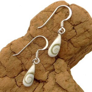Op de afbeelding: Een paar zilveren oorbellen met een witte en groene schelp hanger. De schelp heeft een spiraalvormig patroon.