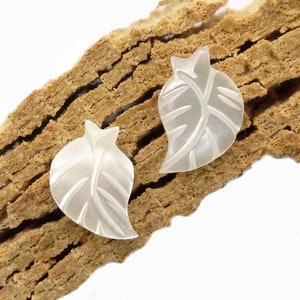 May include: A pair of white mother of pearl leaf shaped earrings. The leaves have a carved design.