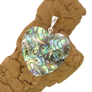 Könnte beinhalten: Ein herzförmiger Anhänger aus schillerndem Abalone-Muschel, mit einer silbernen Öse. Die Muschel ist in kleine Quadrate geschnitten und in einem Mosaikmuster angeordnet.