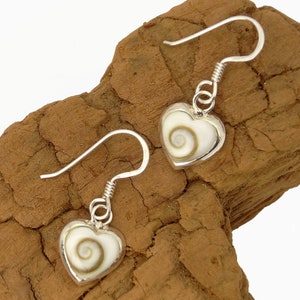 May include: A pair of silver earrings with a heart-shaped shell pendant. The shell is white with a brown swirl pattern.