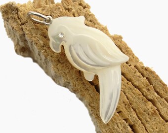 Könnte beinhalten: Ein weißer Perlmutt-Papageien-Anhänger mit einem kleinen klaren Strassstein auf dem Kopf. Der Anhänger ist an einer silbernen Kette.