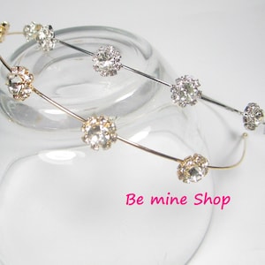 Könnte beinhalten: Zwei silberne und goldene Haarbänder mit klaren Strasssteinen. Die Haarbänder werden auf einer durchsichtigen Glasfläche präsentiert. Der Text "Be mine Shop" ist in der rechten unteren Ecke des Bildes sichtbar.