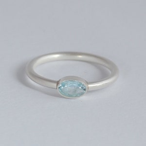 Könnte beinhalten: Ein silberner Ring mit einem hellblauen ovalen Edelstein.