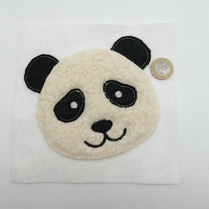 Könnte beinhalten: Weißer Panda-Gesichts-Applikationen mit schwarzen Ohren, Augen und Nase. Die Applikation ist aus flauschigem Stoff und etwa so groß wie eine 1-Euro-Münze.