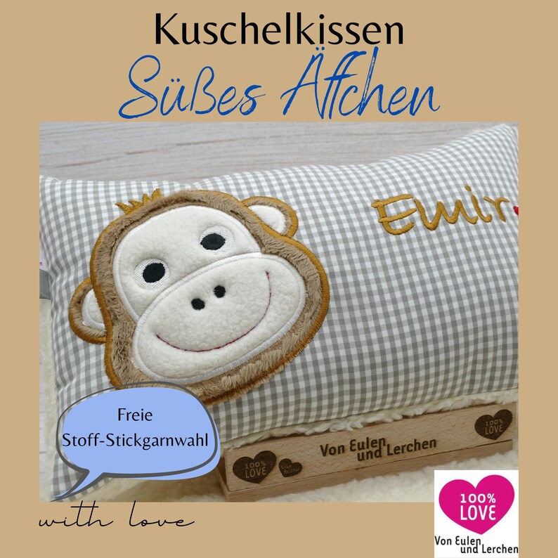 May include: A gray and white gingham pillow with an embroidered monkey face. The pillow has the name "Emir" embroidered in gold thread. Text on the pillow reads "Kuschelkissen S&uuml;&szlig;es Affchen" and "Freie Stoff-Stickgarnwahl".