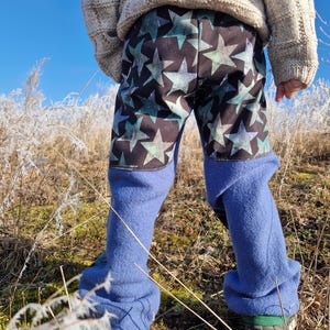 May include: Blue fleece-lined pants with a black and green star pattern. The pants have a fold-over cuff at the bottom.