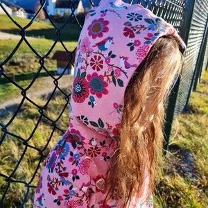May include: A pink hooded sweatshirt with a floral and bird print. The sweatshirt is made of soft, comfortable fabric and features a drawstring hood.