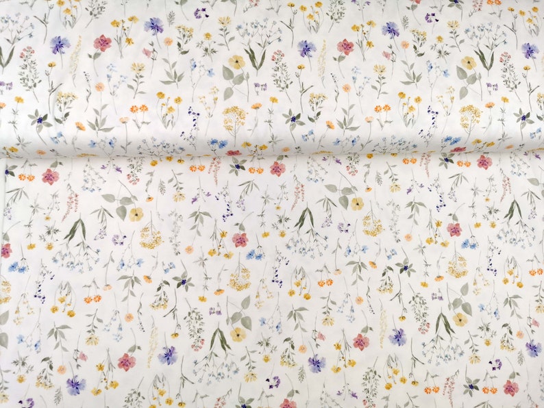 May include: White fabric with a delicate floral pattern featuring small, scattered flowers in shades of pink, yellow, blue, and green.