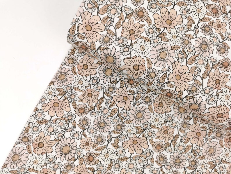 May include: A white fabric with a brown and pink floral pattern. The fabric is covered in small and large flowers.