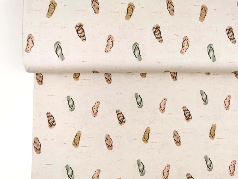 May include: A white fabric with a repeating pattern of brown, green, and pink flip flops. The flip flops are scattered randomly across the fabric.