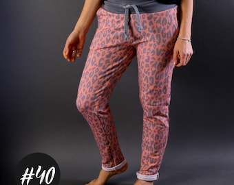 May include: A pair of pink and grey leopard print sweatpants with a grey waistband and drawstring. The sweatpants have a cuffed hem.