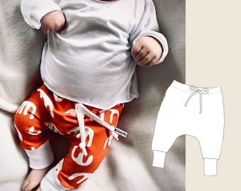 May include: A baby wearing a white long-sleeve shirt and orange pants with a white pattern. The pants have a white drawstring. The baby is sitting on a white blanket. A white outline of a pair of pants with a drawstring is shown on the right side of the image.