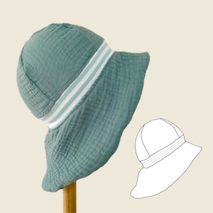 Könnte beinhalten: Ein grüner Sonnenhut mit weißen Streifen um die Krone. Der Hut ist aus einem weichen, strukturierten Stoff gefertigt und hat eine breite Krempe.