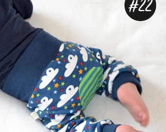 May include: Blue baby pants with a white cloud and star pattern. The pants have a green and blue striped patch on the back. The pants have a tag that says "#22".