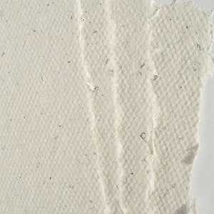 Detailaufnahme: 4 cremefarbene Büttenkarten liegen aufgefächert aufeinander, das Bild zeigt ca. das obere rechte Viertel, sodass man die Büttenränder aus der Nähe sehen kann.
