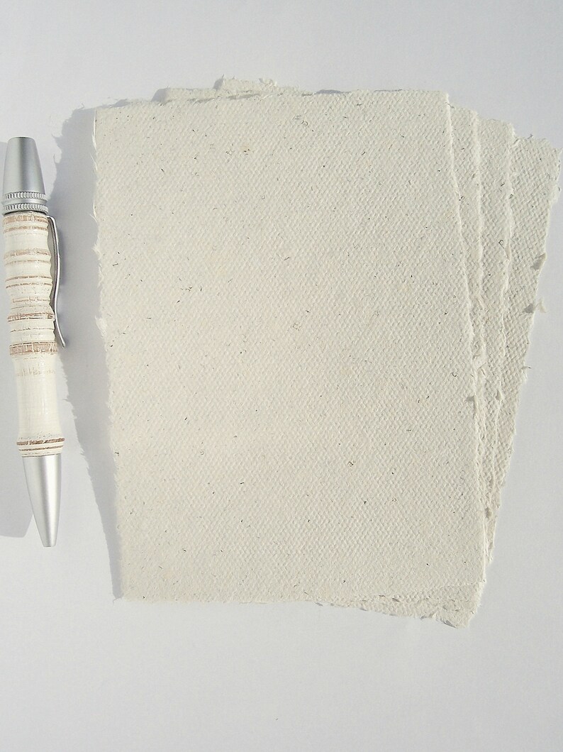 4 cremefarbene Büttenpapier-Postkarten liegen aufgefächert auf dem Tisch, links daneben ein Kugelschreiber zur Veranschaulichung der Größe.