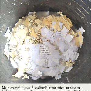Blick von oben in einen schwarzen Eimer, in dem Schnipsel von bedruckten weißen Seiten und von alten cremefarbenen Buchseiten mit unterschiedlichem Schriftbild in Wasser eingeweicht werden. Die Bildunterschrift informiert: "Mein cremefarbenes Recycling-Büttenpapier entsteht aus bedruckten weißen Büropapieren und Resten alter Buchseiten. Jedes Mischungsverhältnis ist individuell verschieden."