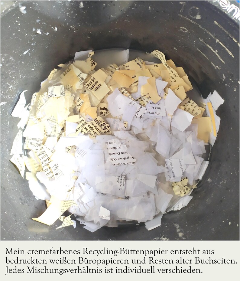 Blick von oben in einen schwarzen Eimer, in dem Schnipsel von bedruckten weißen Seiten und von alten cremefarbenen Buchseiten mit unterschiedlichem Schriftbild in Wasser eingeweicht werden. Die Bildunterschrift informiert: "Mein cremefarbenes Recycling-Büttenpapier entsteht aus bedruckten weißen Büropapieren und Resten alter Buchseiten. Jedes Mischungsverhältnis ist individuell verschieden."
