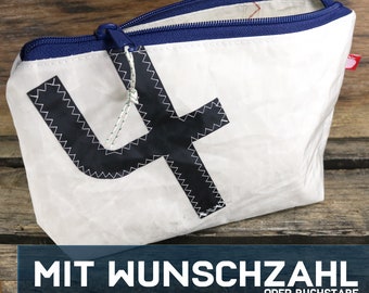 May include: White canvas zippered pouch with a navy blue zipper and trim. The pouch has a large black number "4" printed on the front. The text "MIT WUNSCHZAHL ODER BUCHSTABE" is printed on a blue banner at the bottom of the image.