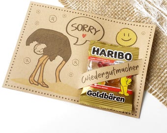 May include: A brown card with an ostrich illustration, the word "SORRY" in a speech bubble, and a smiley face. A small bag of Haribo Goldbears candy is attached with a ribbon.